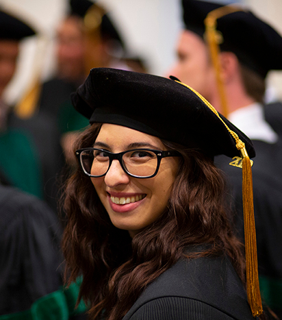 Student smiling dressed in a cap and gown.
