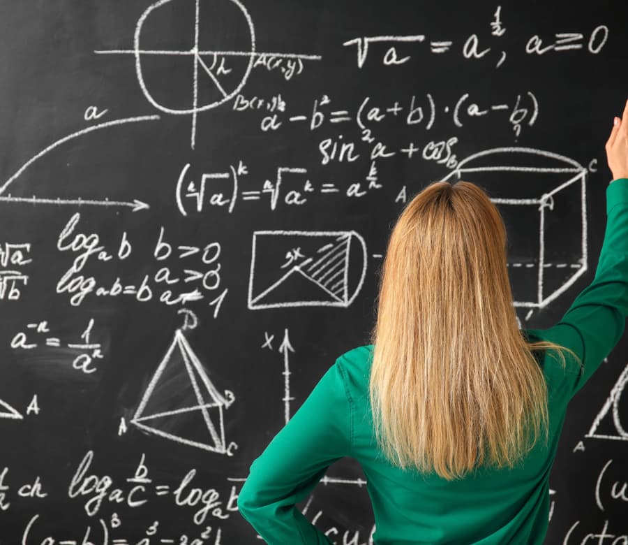 Image of a teacher standing at chalkboard, drawing complex math equations 