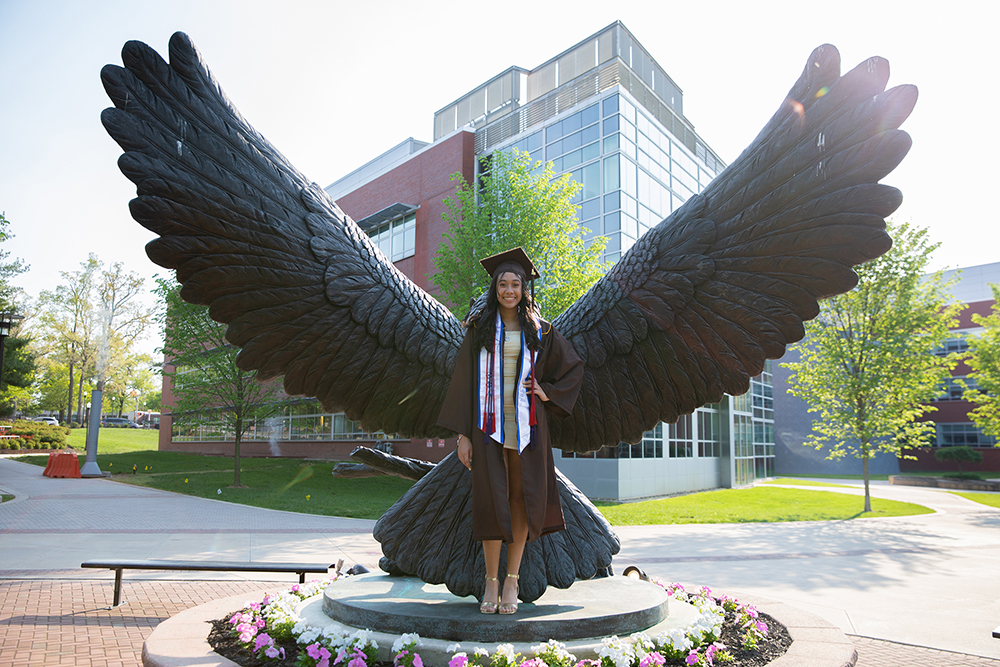 graduating student in front of owl statue