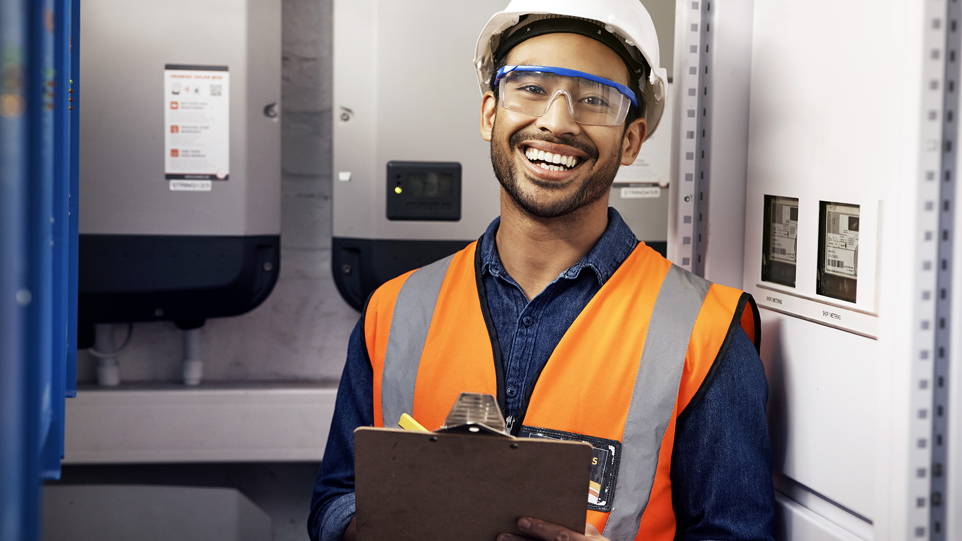 Electrical engineer in hardhat and vest working on electrical panel.