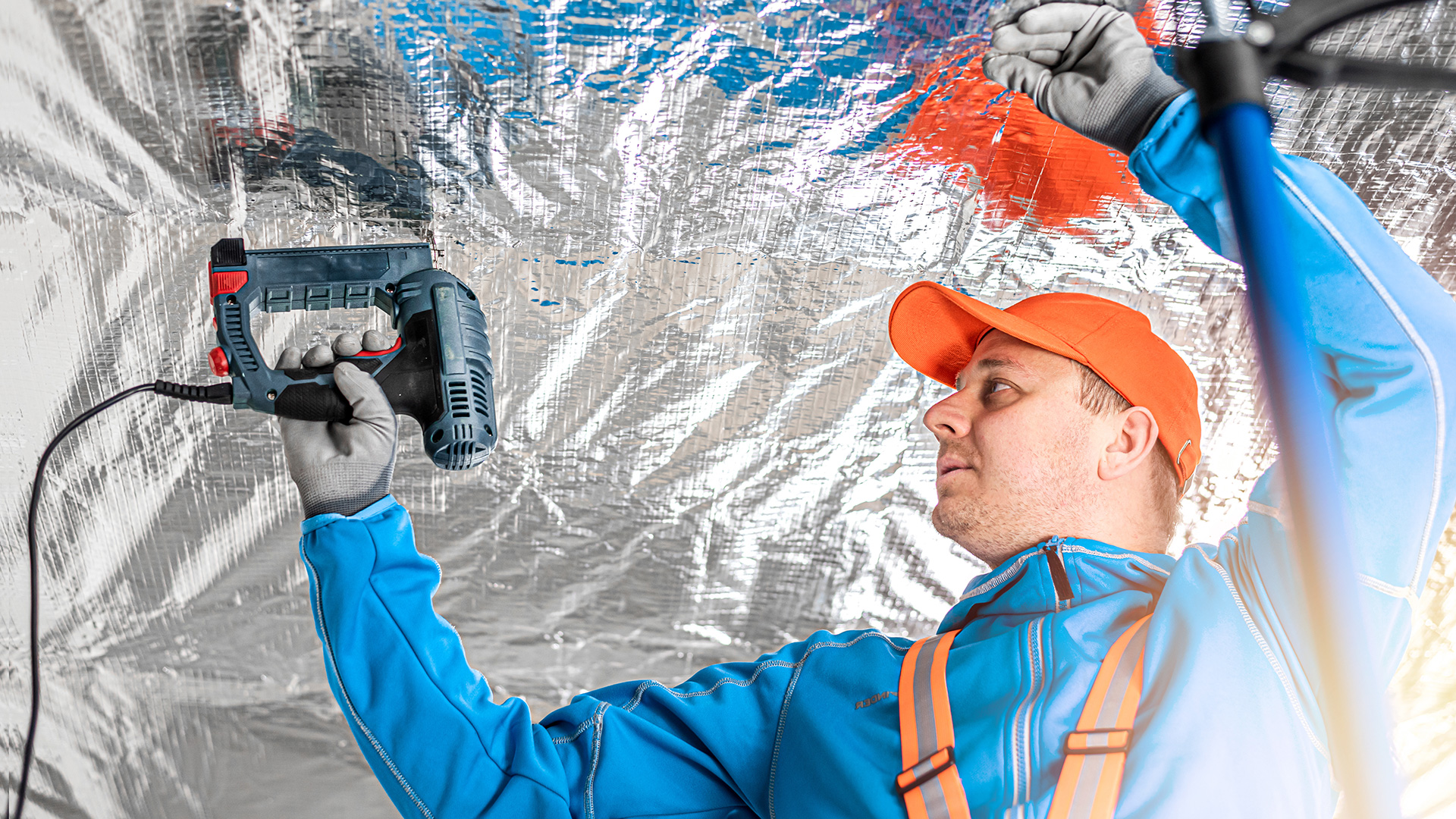 Worker in hat installing overhead insulation