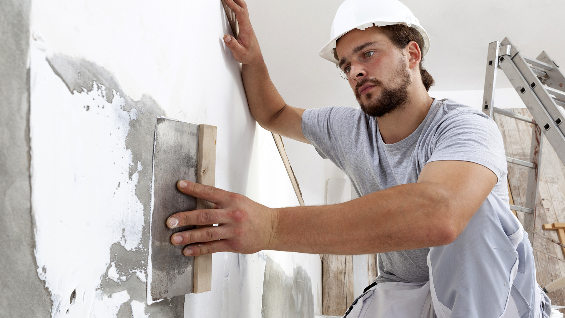 Plaster worker smoothing out wall.