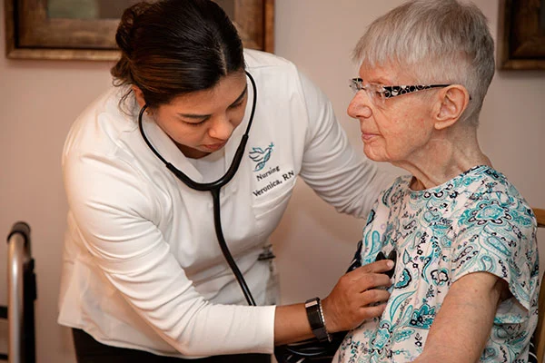 nurse with a stethoscope checking patient's heart