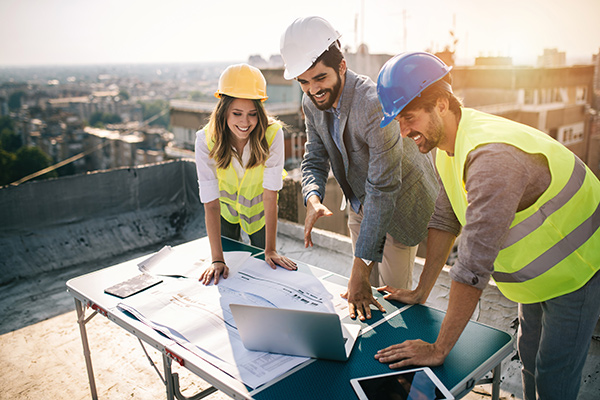 Group of construction workers reviewing blueprints at construction site.
