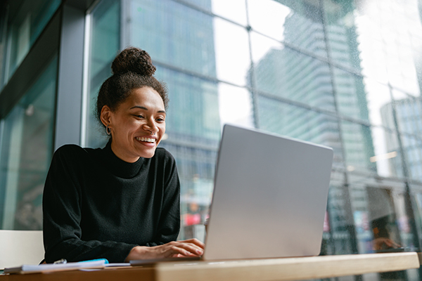 woman in office setting near skyscrapers sitting in front of an open laptop