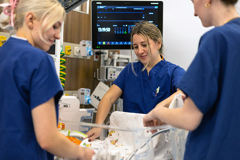 three nurses checking on baby in nicu