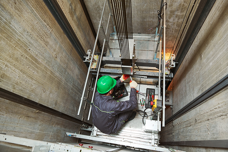 engineering in hard hats repairing elevator in elevator shaft