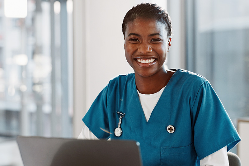 Nursing student smiling while working on a laptop.