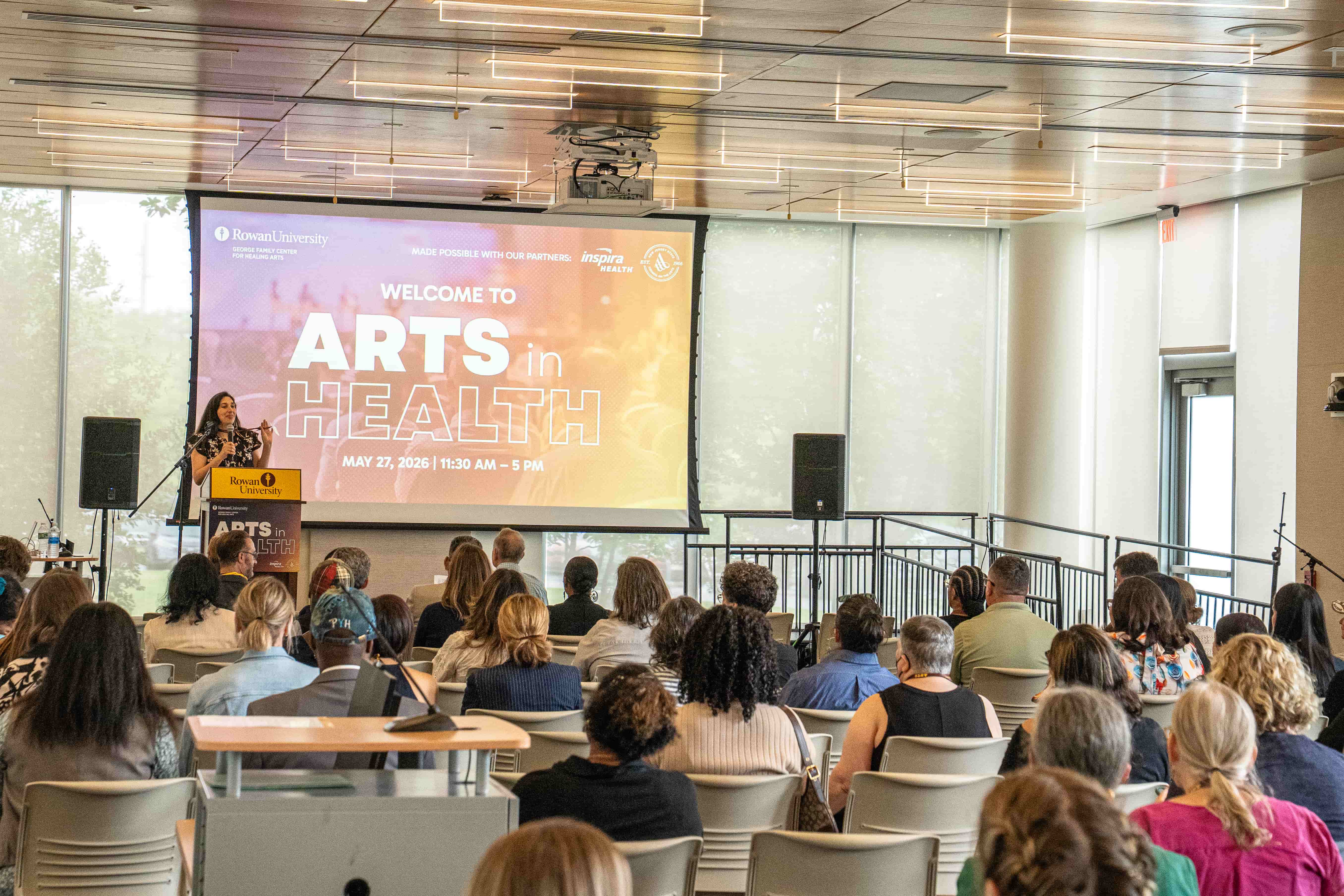 Girl standing next to sign that says Welcome to Arts in Health Conference