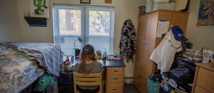 back of female student sitting at desk in dorm room in Chestnut Hall at Rowan University