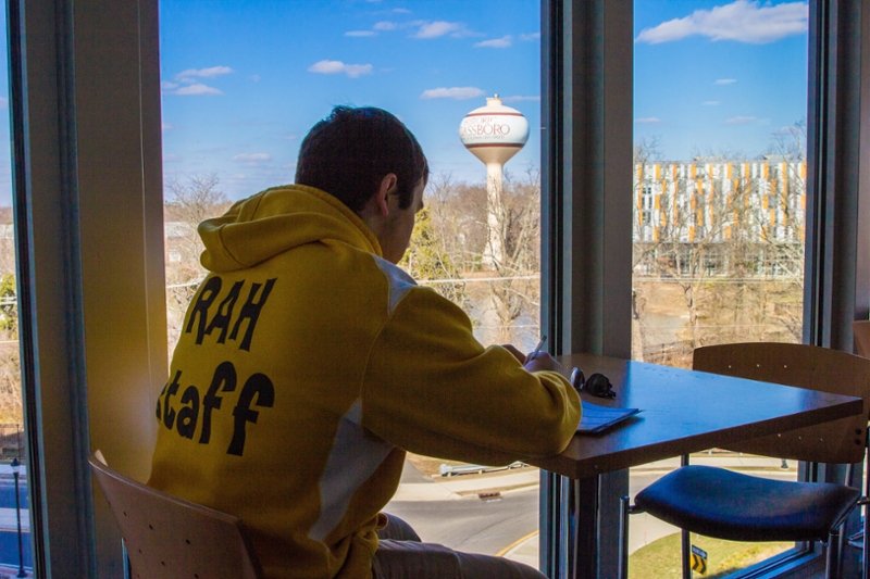 back of sweatshirt of student facing Holly Pointe and water tower through window