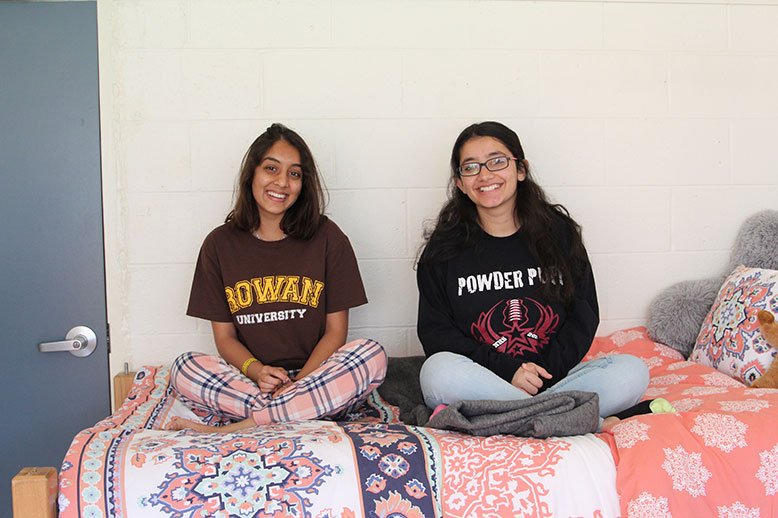 Two Rowan University students sit on a bed in Mullica Hall