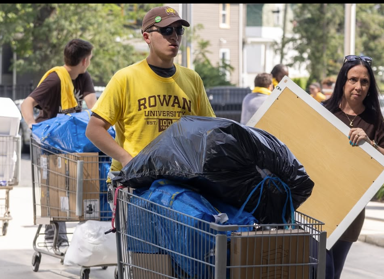 A student pushing belongings in a moving cart across campus. 