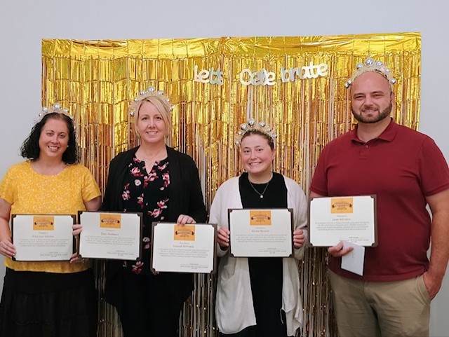 Prof of the Month Rowan Online Student Success Coaching Team standing in front of a gold banner and a sign that says "let's celebrate!"