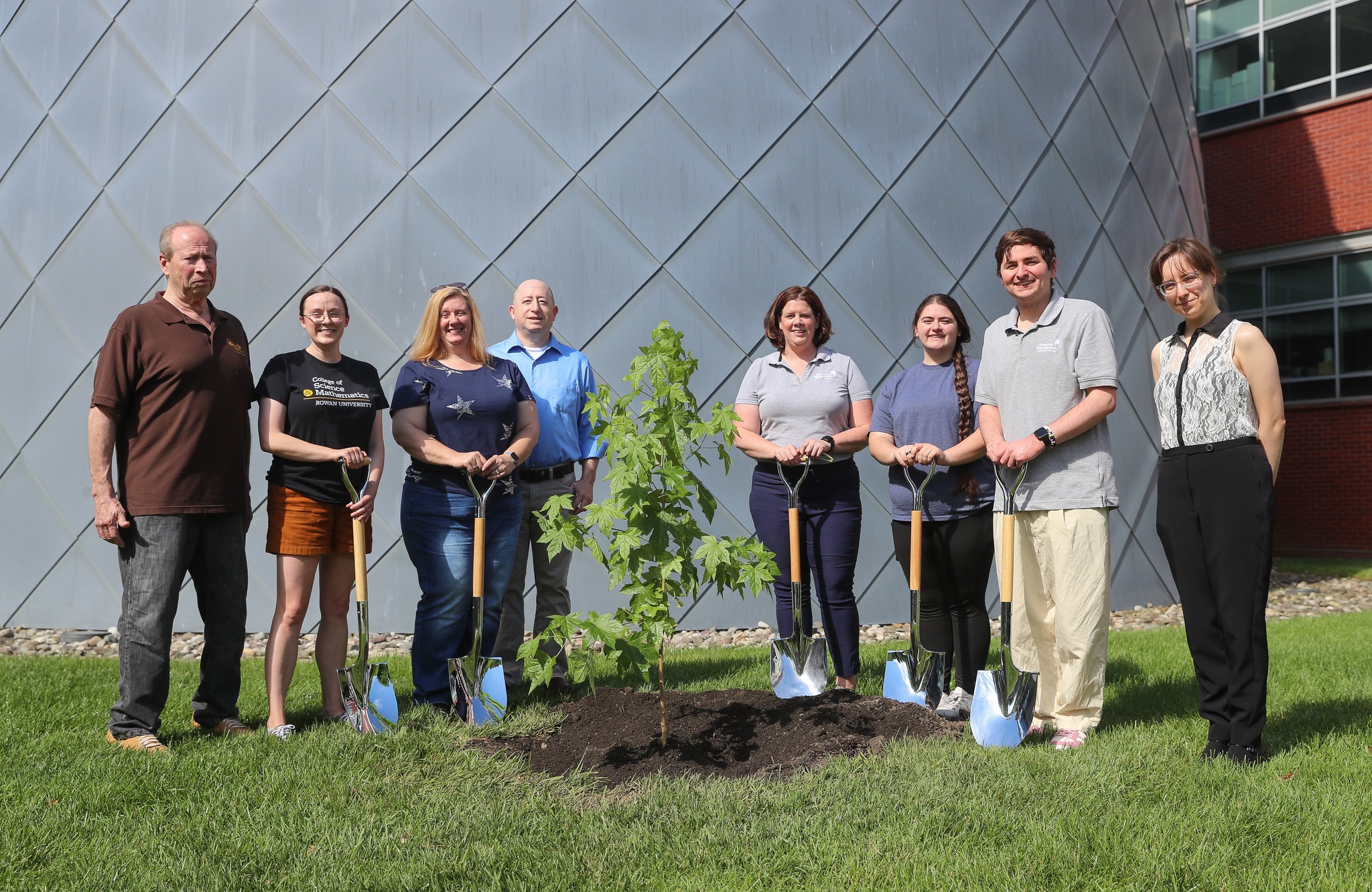 Edelman Planetarium staff pose for a picture with a tree sapling. Each person is holding a ceremonial shovel.
