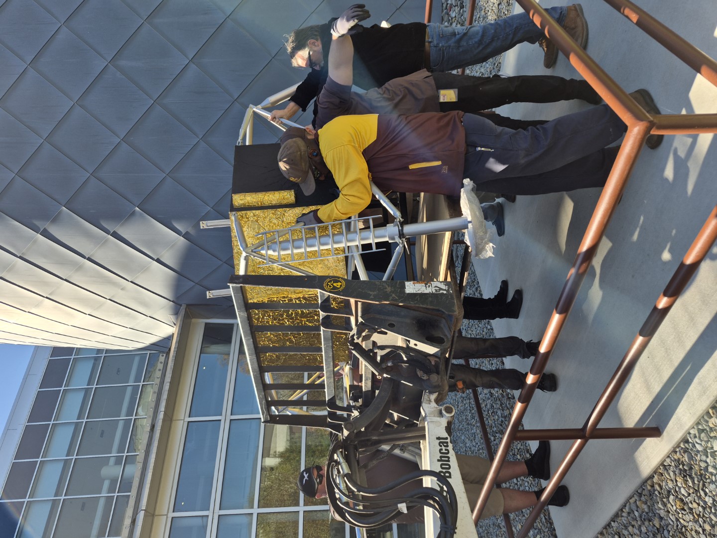 The lander base is supported by 8 crew members before being lowered into position.