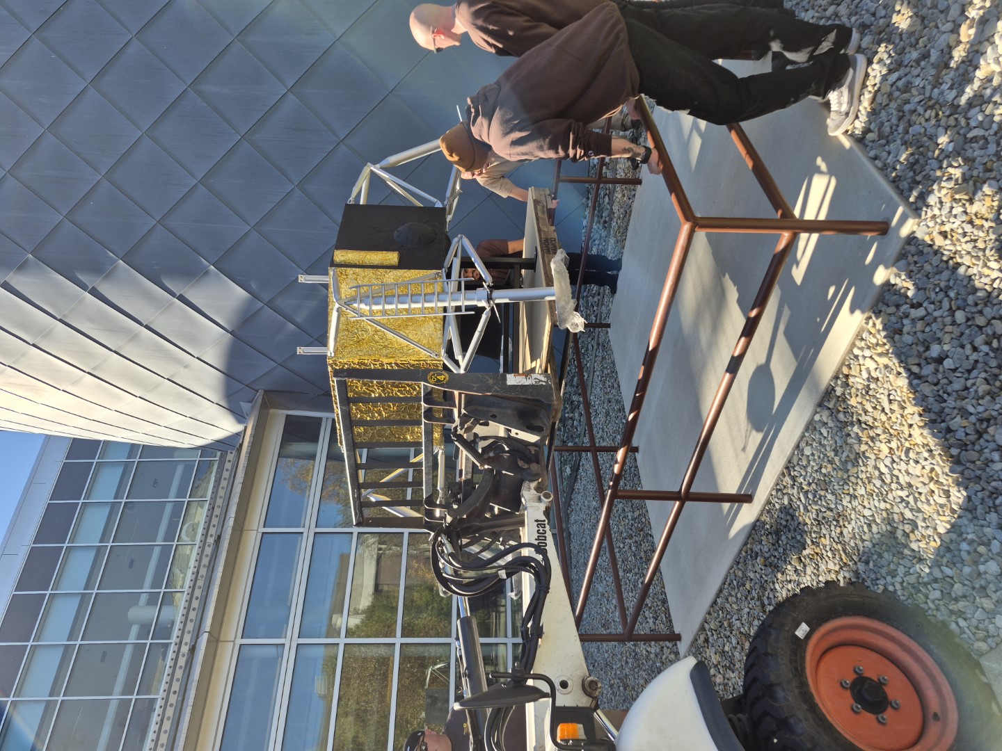 A crew of workers stands around the bottom piece of the lunar lander as it is positioned over the pad.