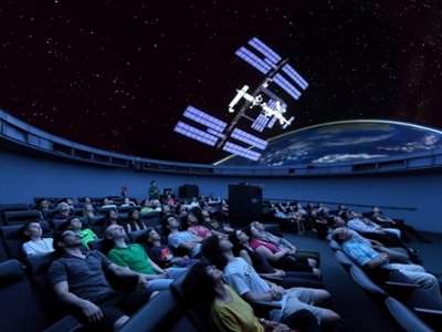 An audience views the International Space Station on the Edelman Planetarium dome screen.