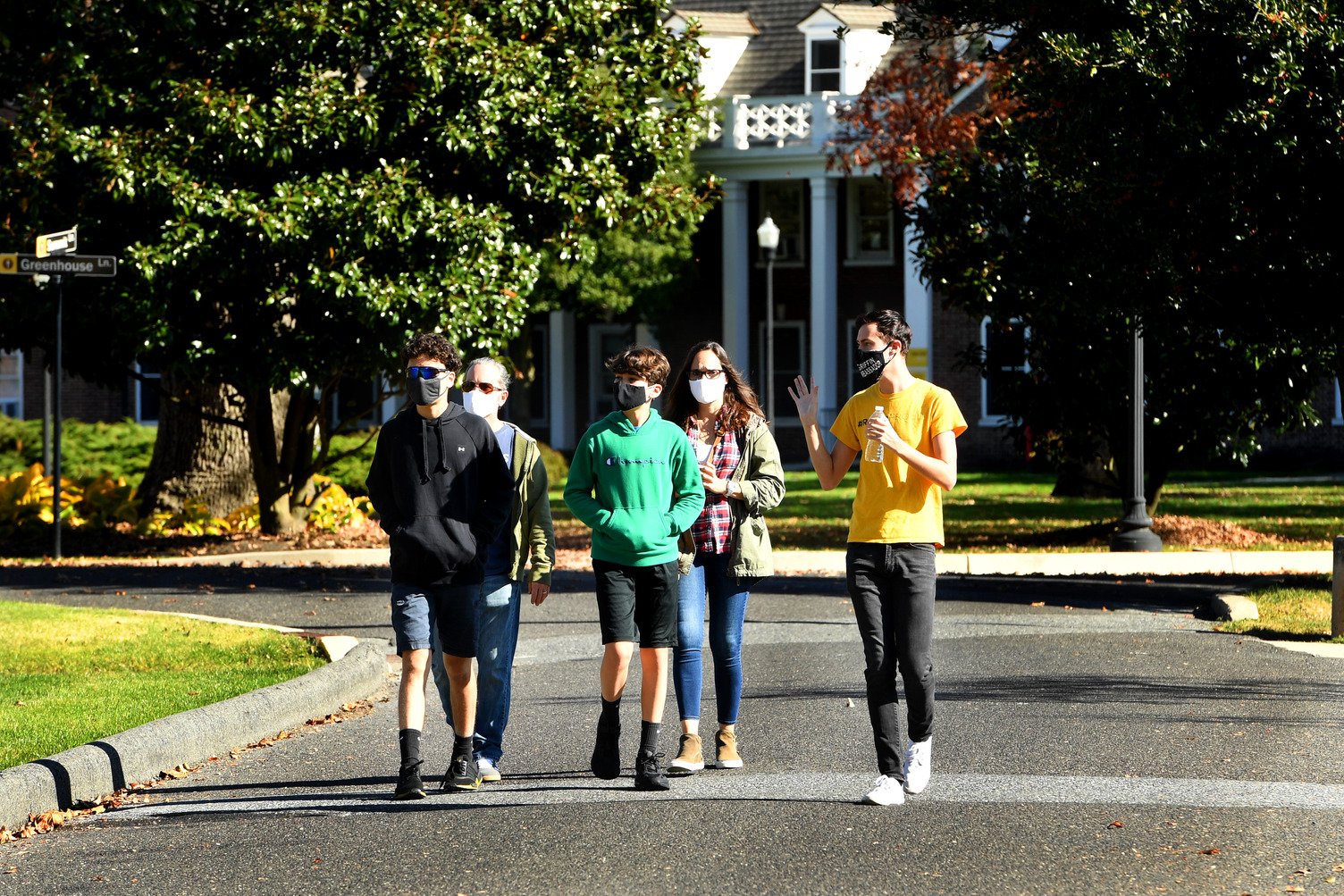 Five individuals walk around campus wearing face masks