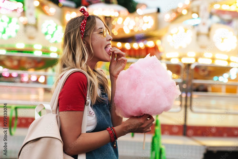 Person holding cotton candy in front of carousel