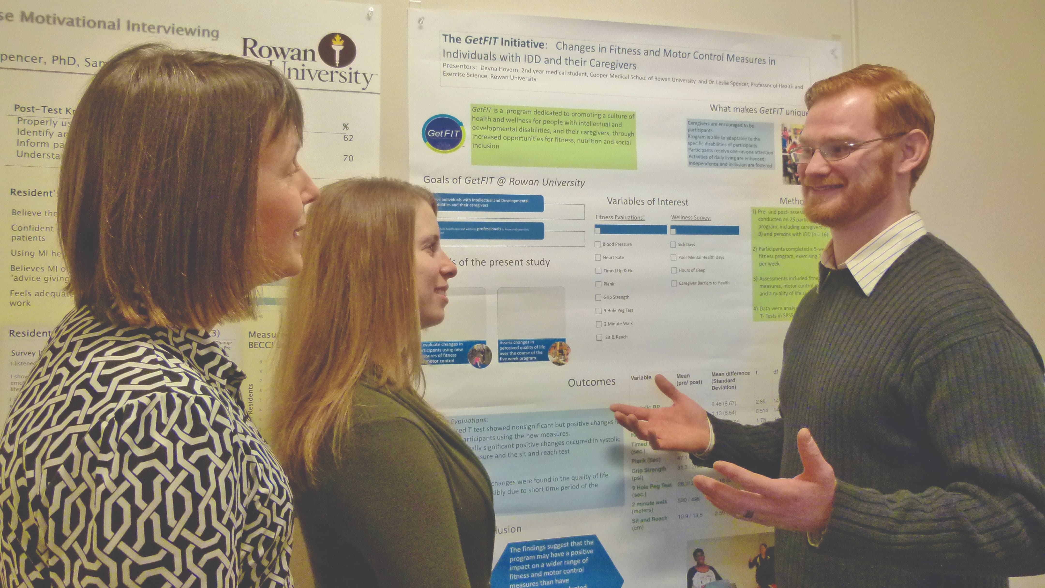 photo of faculty and students discussing a research poster