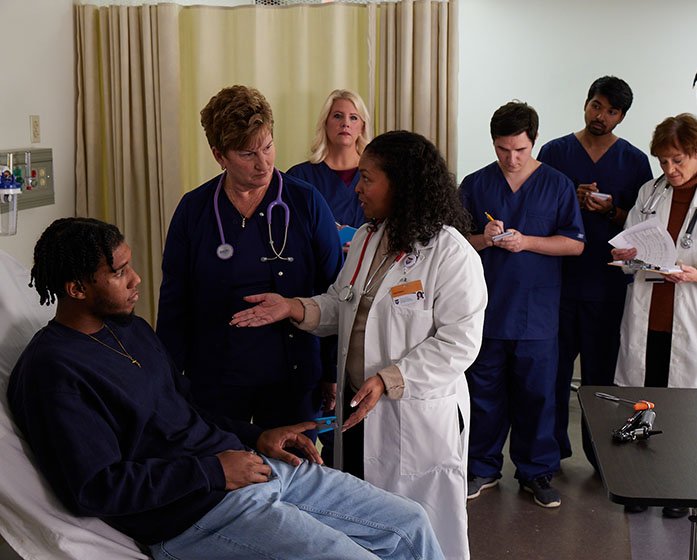 nursing students and faculty work with a patient-actor