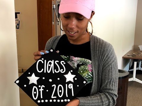 A woman holding a graduation cap that is decorated to read "Class of 2019."