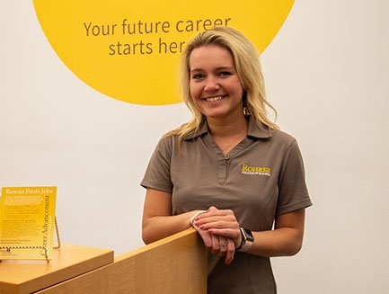 A smiling student wearing a Rowan shirt at a professional development event.