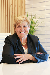 Theresa Drye smiles and leans her crossed arms on her desk