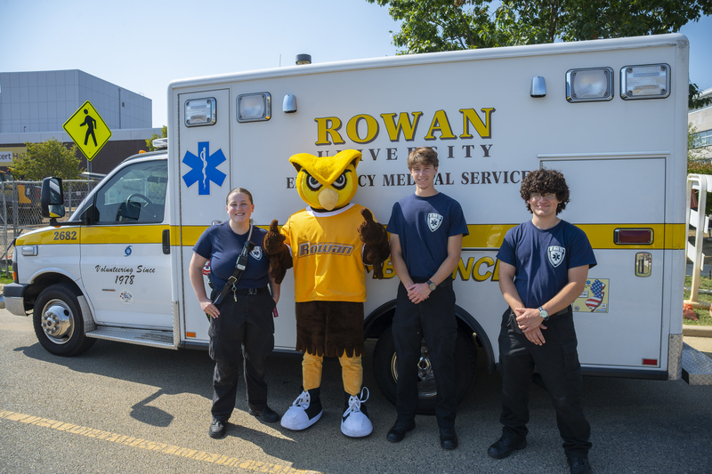 ems students in front of ems ambulance with school's mascot Whoo RU