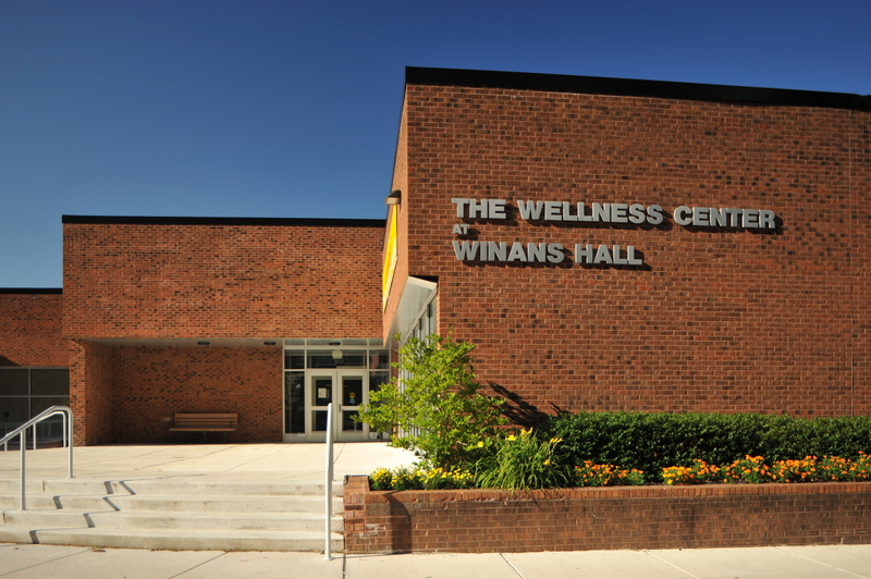 A picture of the wellness center building outside with specifically the signage "wellness center winans hall" in photo